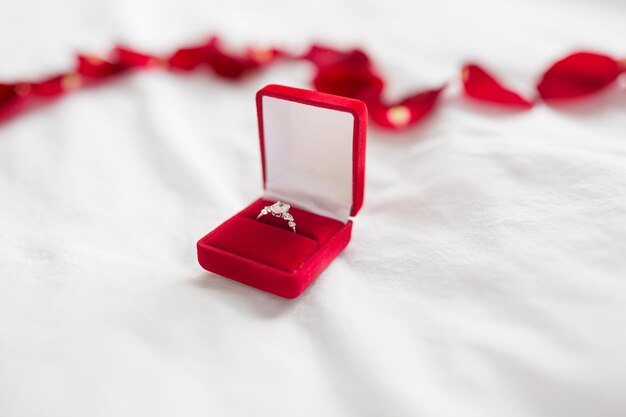 diamond ring in red velvet gift box on bed sheet