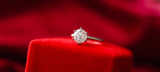 Diamond ring with jewelry gift box on red fabric background