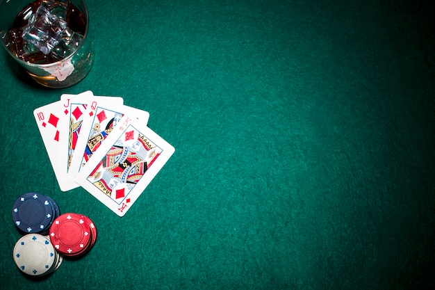 Diamond royal flush speelkaart; casino chips en whisky glas met ijsblokjes op groene achtergrond