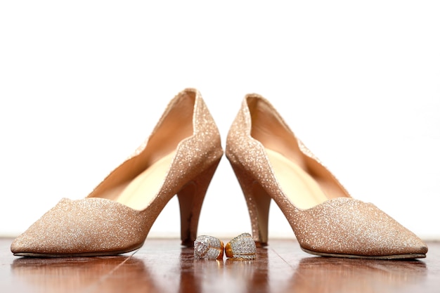 Diamonds ring and golden color shoes for wedding on wooden.