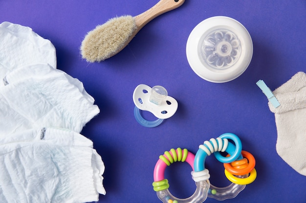 Diaper; brush; pacifier; milk bottle; sock and rattle on blue background