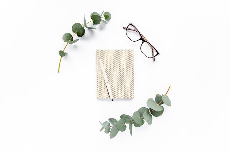 Photo diary pen green leaves eucalyptus and glasses on white background flat lay top view