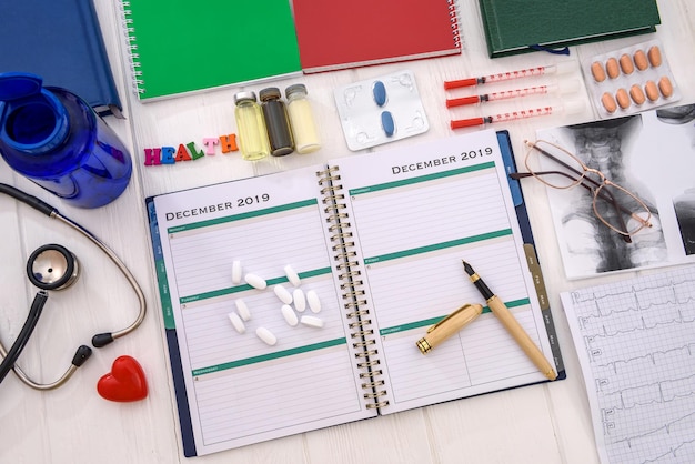 Diary with pills and notepads on table close up