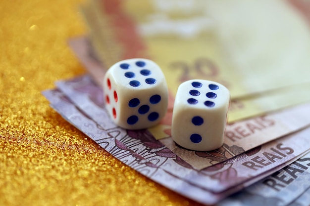 Dice cubes with Brazilian money bills on golden glitter background Concept of luck and gambling in Brazil