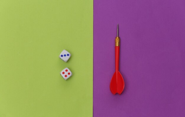 Dice and darts on purple green background. Top view