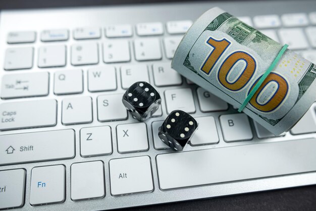 Dice and dollar bills on a new laptop keyboard isolated on a black table