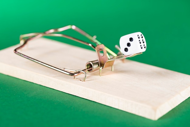 Dice and mousetrap, game trap, on a green background, get into gambling addiction.