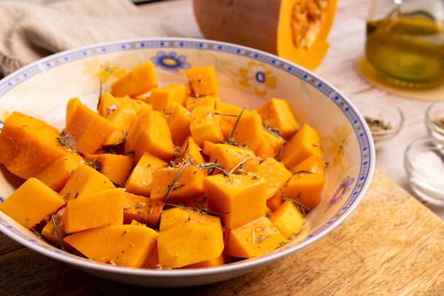 Diced pumpkin pieces in a bowl with spices and olive oil