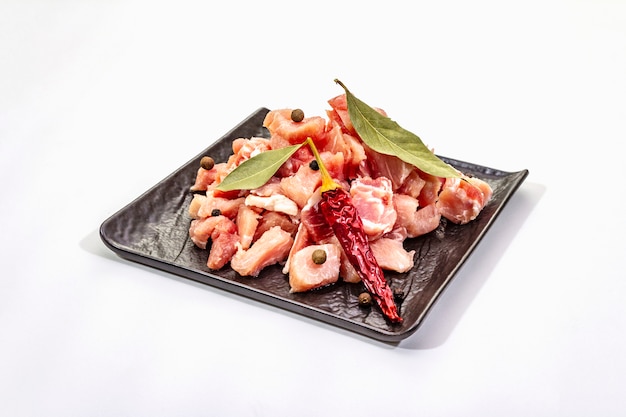 Нарезанное кубиками сырое мясо свинины с сухими лавровыми листьями и перцем чили