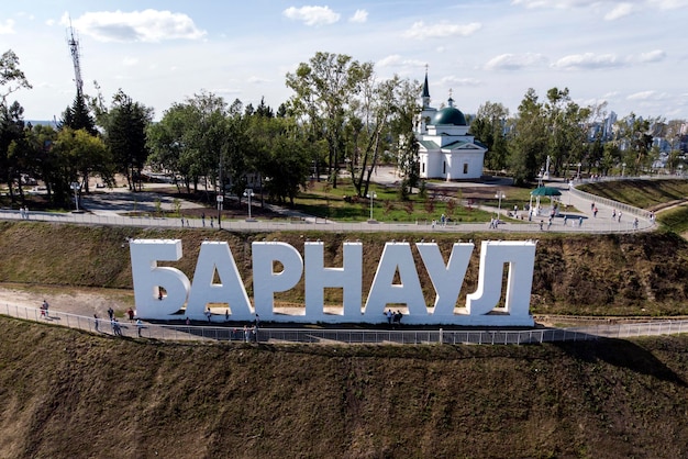 Dichtbij de heuvel met de letters die de naam van een Russische stad beschrijven, een park en een kerk op de achtergrond. Het herkenningspunt en architectonisch merk van de stad. Populaire recreatieplek onder burgers