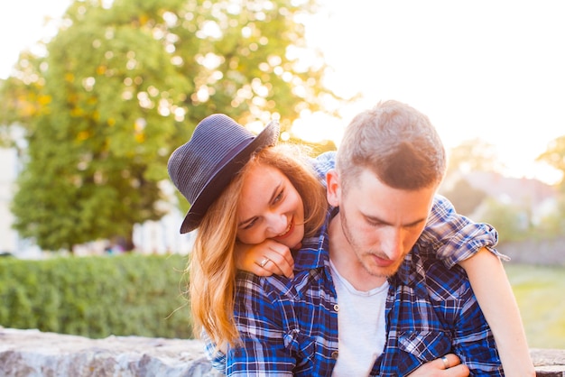 Dichte mening van jong paar. Vrouw die op de schouders van haar partner rust, glimlacht en probeert zijn aandacht te trekken. Zomer in de stad. Lange dag samen. wandeling in de oude romantische stad