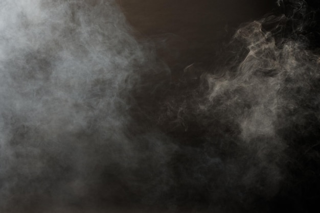 Dichte pluizige rookwolken van witte rook en mist op zwarte achtergrond, abstracte rookwolken, beweging wazig onscherp. Rokende blaasjes van machine droogijsvliegen en fladderen in lucht, effect textuur