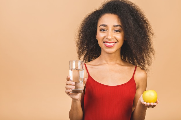 Dieet concept. Jonge vrouw op beige met een appel en met een glas water.