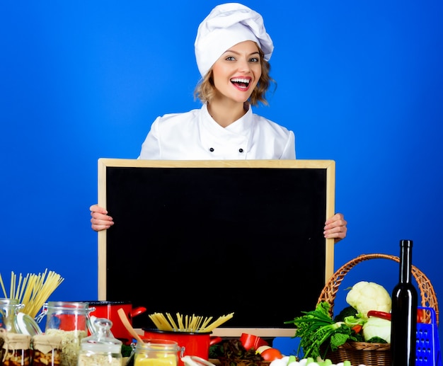 Dieet gezonde levensstijl vrouw chef houdt een zwart bord voor uw tekst voedselbereiding glimlachende chef