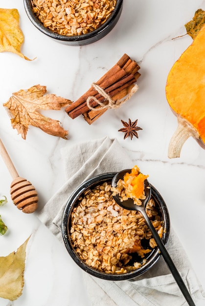 Dieet herfstgebak, ontbijt. Crumble-pompoentaart, ahornsiroop en havermoutvlokken, in schoteltjes, op een witte marmeren tafel. Kopieer ruimte