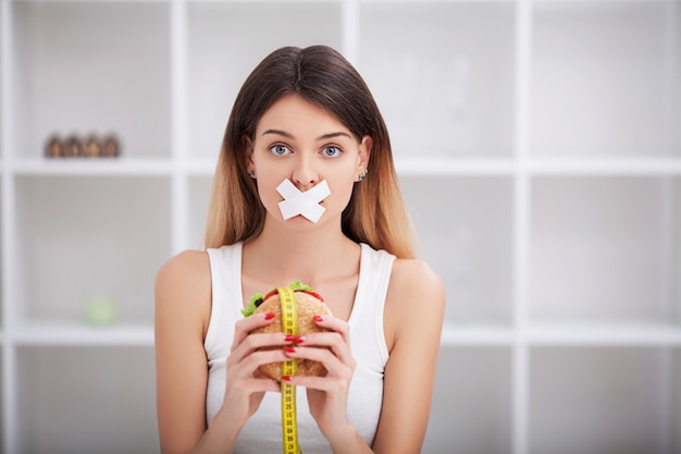 Dieet. Het van gezonde en ongezonde voeding. Het grote model maakt een keuze voor gezond eten en fruit door fast food en hamburger te weigeren. XXL vrouw