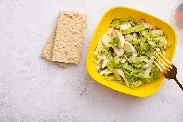 Dieetbroden en salade van verse groenten en krabstokken in een plastic container Het concept gezond eten