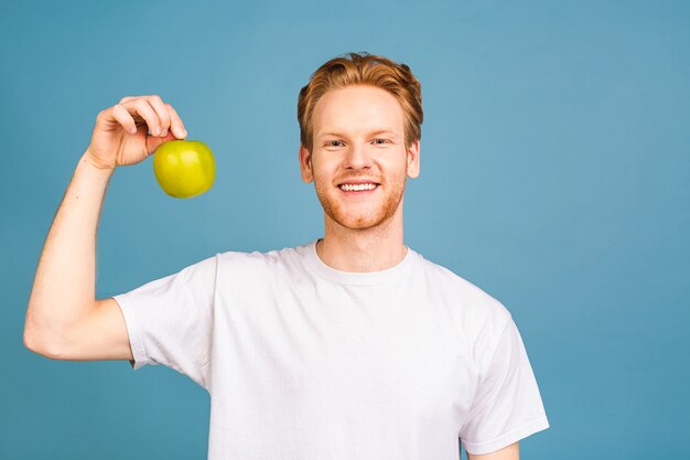 dieetconcept en gezonde levensstijl. vrolijke mooie jonge man die appel eet,