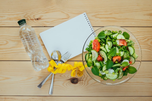 Foto dieetplan, meetlint, fles water en salade