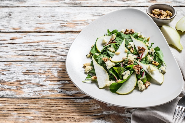 Dieetsalade met blauwe gorgonzola-kaas, peren, noten, snijbiet en rucola. witte achtergrond. bovenaanzicht. kopieer ruimte.