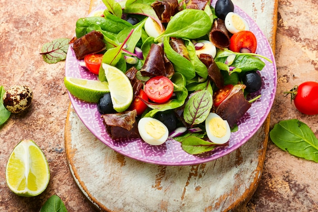 Dieetsalade van snijbiet, kwarteleitjes, tomaten en schokkerig. Salade met jamon en groenten.