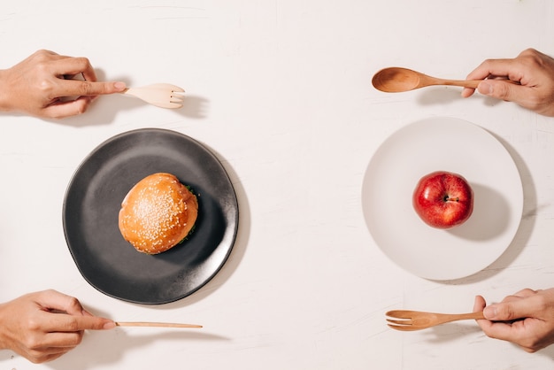 Dieetstrijd en beslissen tussen voedingskeuzedilemma tussen gezond goed vers fruit en groenten of cholesterolrijk fastfood dat concurreert om te beslissen wat te eten handencake en appel kiezen