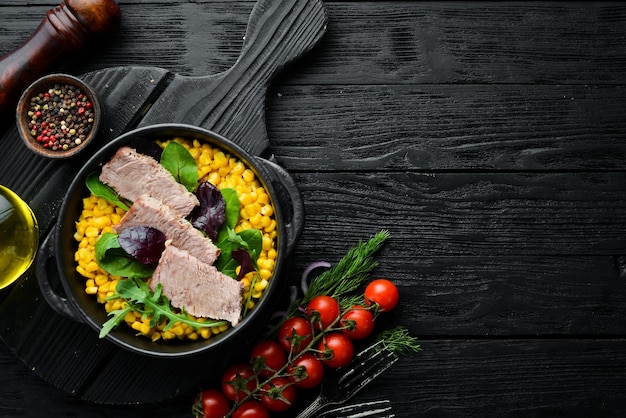 Dieetvoeding Gekookt kalfsvlees met mais en spinazie in een zwarte kom Rustiek