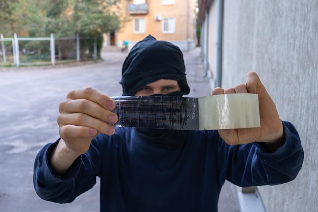 Foto dief man met masker die de cctv-camera buiten vastplakt om in huis te breken