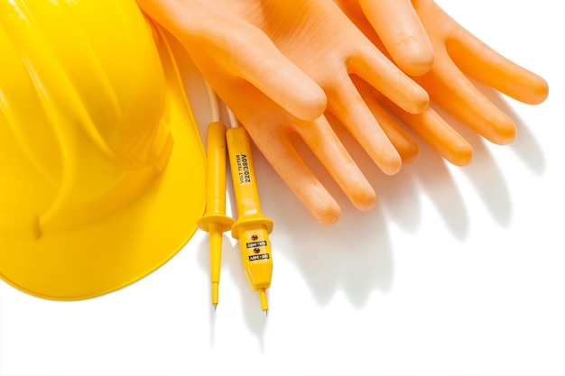 Dielectrical gloves electric tester nad yellow helmaet isolated on white