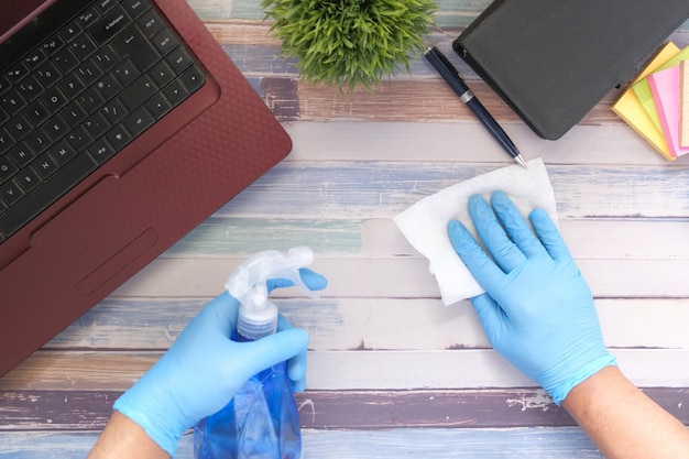 Foto dien blauwe rubberhandschoenen in houdend de schoonmakende lijst van de nevelfles