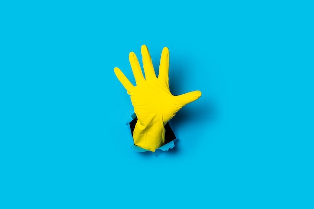 Dien gele handschoen in met een open handpalm, vijf vingers op een helderblauw