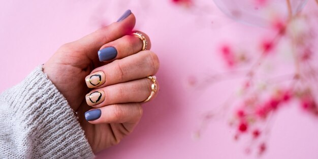 Foto dien trui en roze bloemen in met moderne manicure nagels. vrouwelijke hand. glamoureuze mooie manicure. manicure salon concept. nagellak close-up.