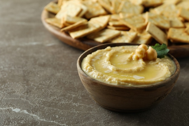 Dienblad met crackers en kom hummus op grijs