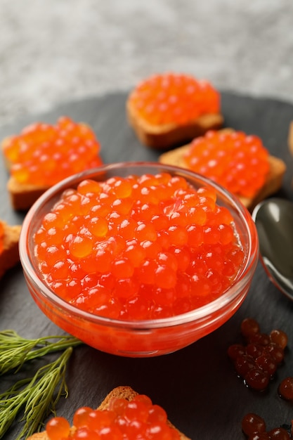 Foto dienblad met snacks en kom met rode kaviaar op grijs