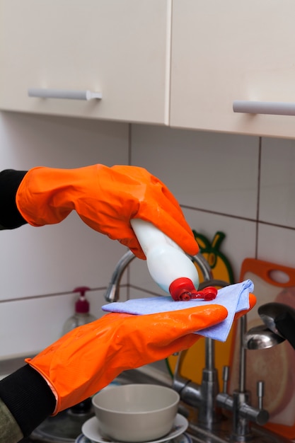 Dient handschoenen in giet wasvloeistof in de keuken