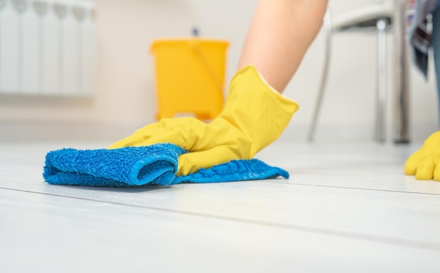 Diepe schoonmaakservice Professionele reiniger wassen witte vloer in de woonkamer van appartement vrouwelijke handen in handschoenen vegen witte vloer met tekst schoonmaken Schoonmaakservice concept