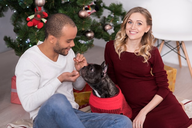 Dieren thuis. Leuke vrolijke optimistische man kijkt naar zijn hond en lacht terwijl hij met hem speelt