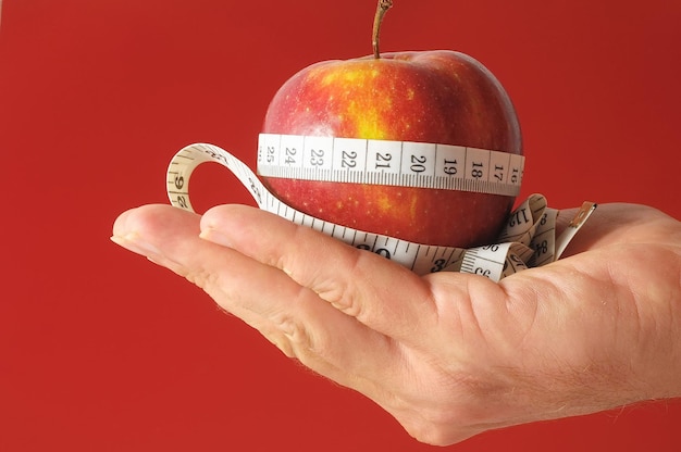 Diet Apple and Meter on the Hand on a Colored Background