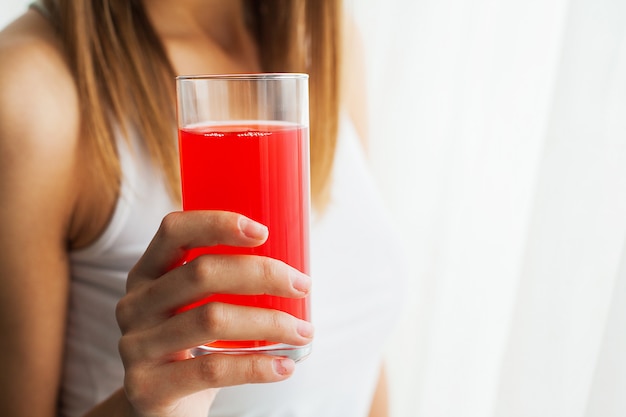 Diet, A beautiful young girl who follows the figure, drinking juice, The concept of healthy eating, White background