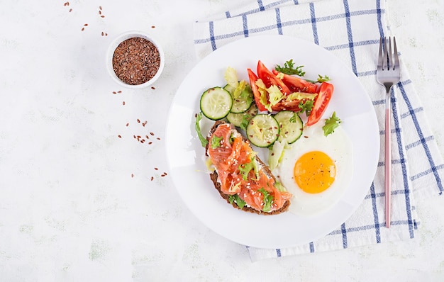 Diet breakfast Fried eggs and sandwiches with salt salmon  and cucumber tomatoes lettuce  Top view overhead