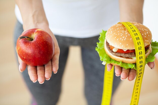 Diet concept, woman holding a choice of harmful hamburger and fresh apple.