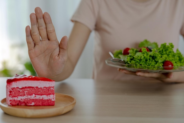 Concetto di dieta le donne rifiutano la torta e mangiano insalata per una buona salute