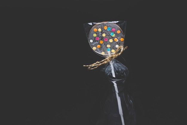 Diet curly lollipops. Transparent and with bright elements. On a stick. On a black background.