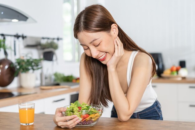 Photo diet dieting pretty slim asian young woman or girl smiling looking at mix vegetables green salad bowl eat vegetarian food is low fat good healthy nutritionist weight loss for health person