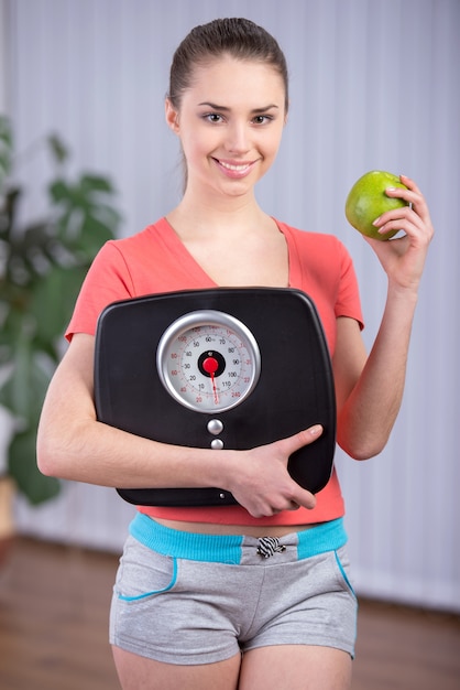 Diet eating woman with scale and apple for weightloss.