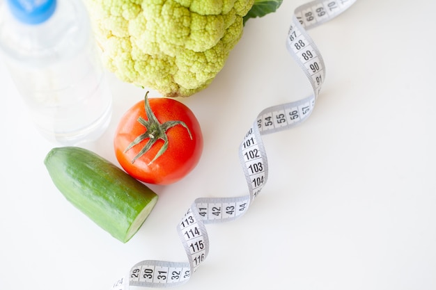ダイエット。フィットネスと健康食品のダイエットコンセプト。野菜とバランスの取れた食事。新鮮な緑の野菜、測定テープ
