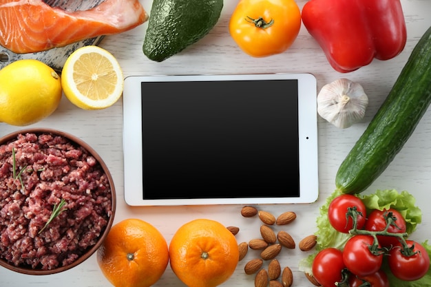 Diet food and tablet on a light wooden background