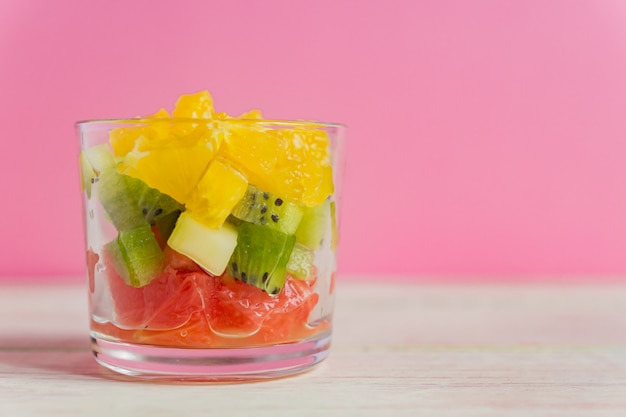 Photo diet fresh tasty mix fruit salad in a glass jar. chopped juicy oranges, kiwi and grapefruits.