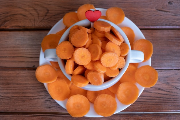 Diet, health, vegetable concept. Round slices of raw carrots in a white bowl on wooden table