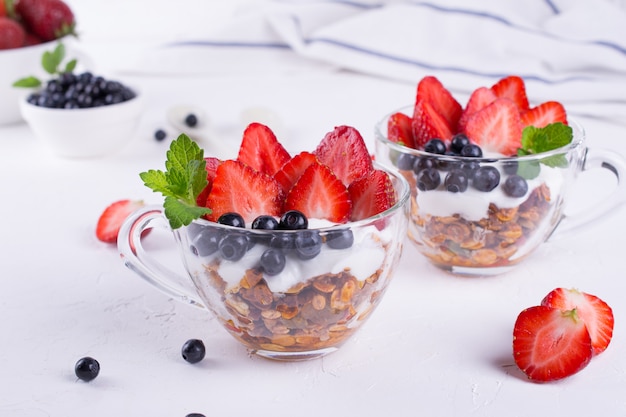 Diet  healthy dessert with yogurt, granola and fresh berries. on white table background